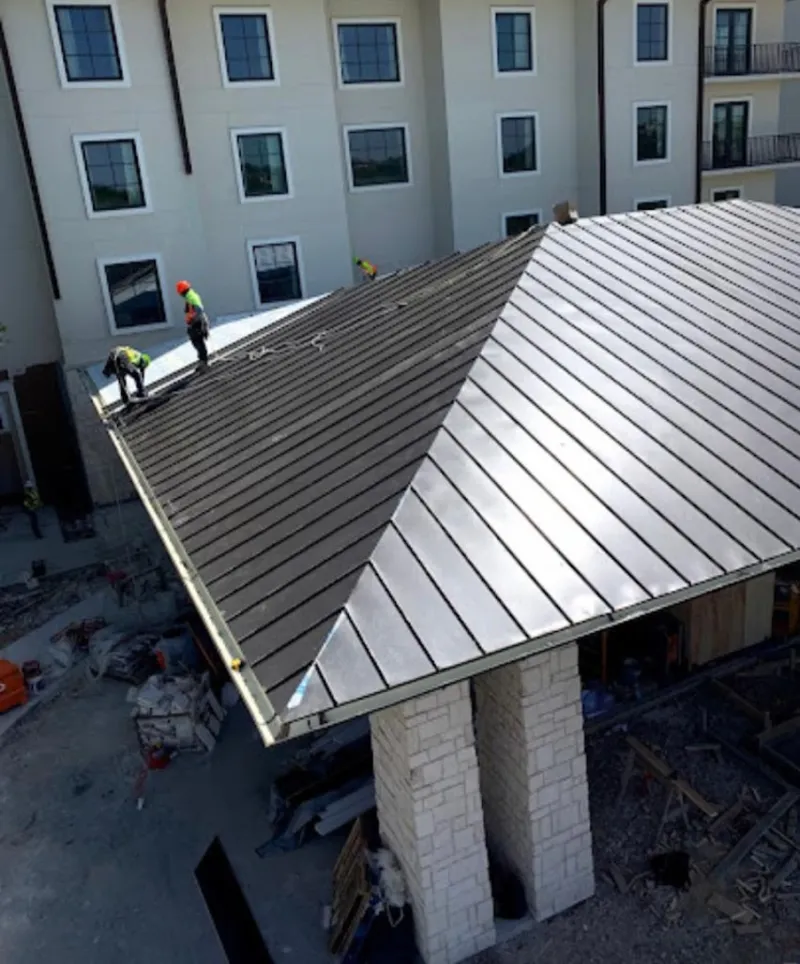 Crew installing standing seam metal roof panels on a commercial project in Payson